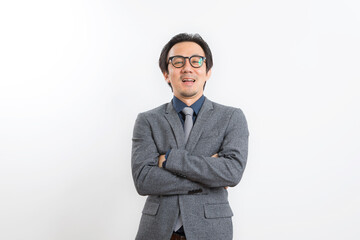 Confident Asian businessman in grey suit and eyeglasses posing with arms crossed standing over white wall background, Business success concept.