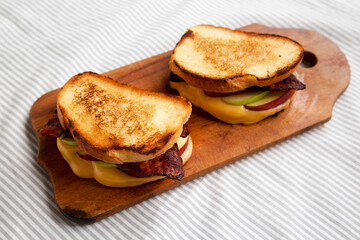 Homemade Bacon Apple Grilled Cheese on a rustic wooden board, low angle view.