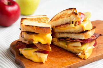 Homemade Bacon Apple Grilled Cheese on a rustic wooden board, side view. Close-up.