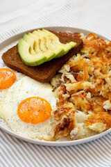 Tasty Homemade Fried Hashbrowns and Eggs on a plate, side view.