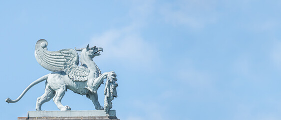 Banner with old statue of medieval griffin, a hybrid of lion and bird, on the top of the State...