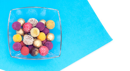 handmade chocolate truffles, different colors on a platter on a blue and white background.