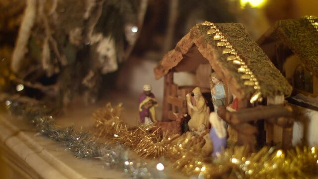 Woman puts miniature figurines in a christmas crib above the fireplace. Beautiful nativity scene and christmas decorations - close view