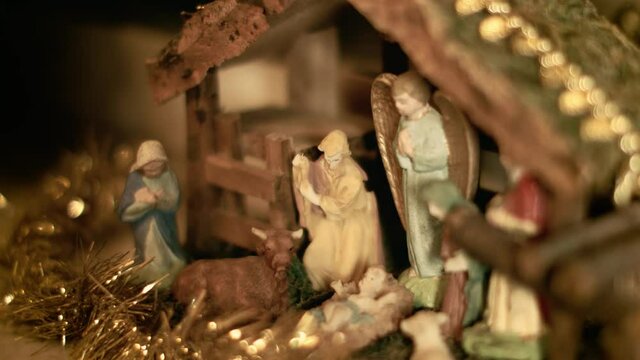 Hand of a woman putting miniature figurines of Mary and Joseph in a christmas crib. Beautiful nativity scene and christmas decorations - close view