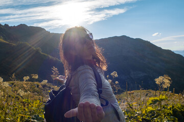 Naklejka premium Happy young woman on nature in the mountains, sun rays and glare.