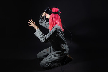 young woman with pink hair and in a jumpsuit uses virtual reality glasses, is in the game,