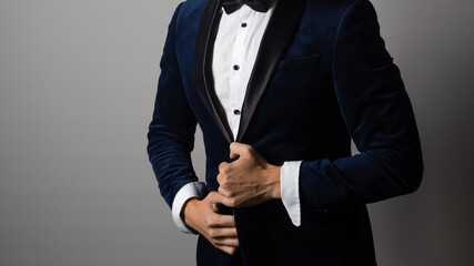man in a tuxedo with a bow tie buttoning his jacket or adjusting his sleeve,