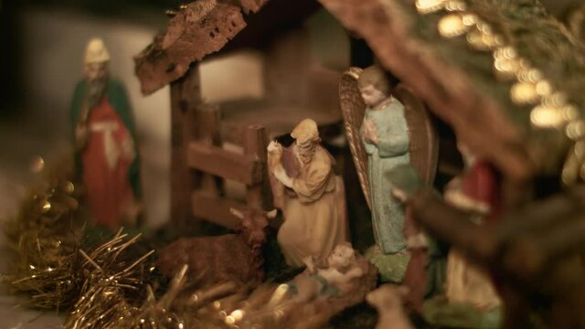 Woman puts miniature figurines of Mary and Joseph in a christmas crib. Beautiful nativity scene and christmas decorations - close view
