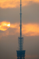 The sun illuminates the TV tower through the clouds.