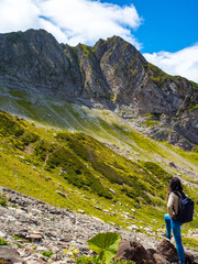 Naklejka na ściany i meble Unity with nature. Hiking in the mountains. Young woman traveling in the mountains,