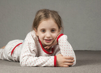 European girl 8 - 10 years old. In pajamas, lies on the floor.