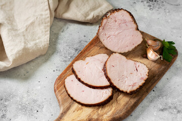 Meatloaf with herbs on a wooden serving Board on a light gray table. Baked meat