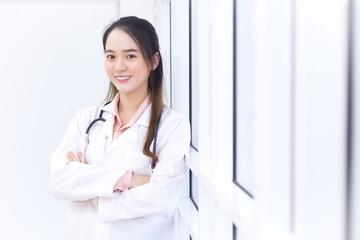 Asian female doctor with black long hair wears a white lab coat and stethoscope.