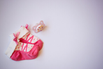 Small newborn baby girls pink socks and pacifier on white background