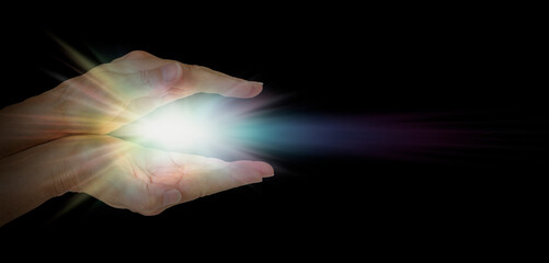The healing hands of a Lightworker - Female parallel hands against pitch black background with a...