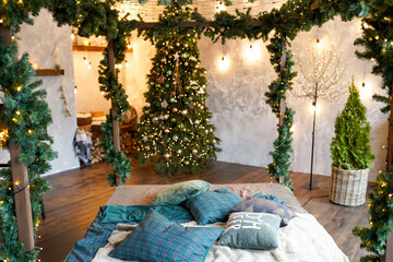 Stylish Christmas interior, bedroom with a lot of lights and christmas tree branches.