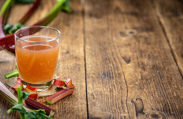 Old wooden table with fresh made Rhubarb Juice (close up; selective focus)