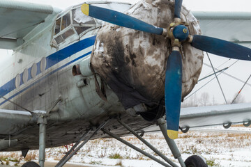 old, vintage plane with a small aircraft propeller at the airfield, airport in the snow in winter