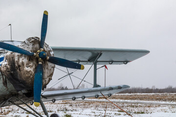 old, vintage plane with a small aircraft propeller at the airfield, airport in the snow in winter