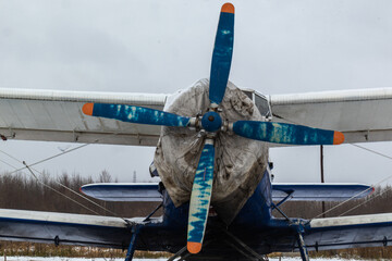 old, vintage plane with a small aircraft propeller at the airfield, airport in the snow in winter