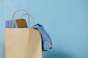 Blue jeans in a paper craft bag on a blue background. Concept of thrift stores, resale, second...
