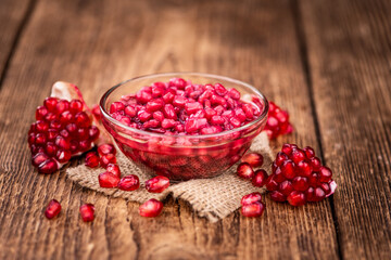 Old wooden table with fresh preserved Pomegranate seeds (close-up shot; selective focus)