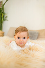 portrait of a baby girl lying on a fur blanket and looking at the camera. Vertical orientation