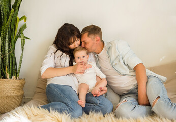 mom, dad and baby girl sitting on the bed