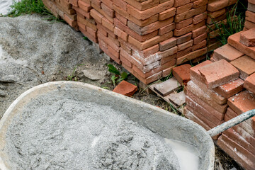 wheelbarrow with abandoned plaster next to a pile of bricks