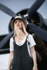 Fototapeta na wymiar woman in a straw hat on the background posing against the backdrop of an airplane with a propeller