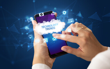 Female hand holding smartphone with TECHNOLOGY TRENDS inscription, cloud technology concept