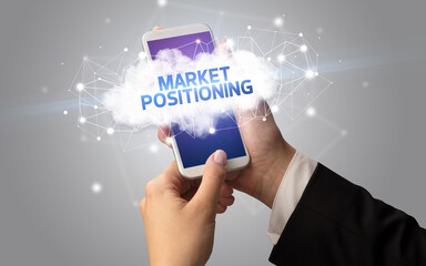 Female hand touching smartphone with MARKET POSITIONING inscription, cloud business concept