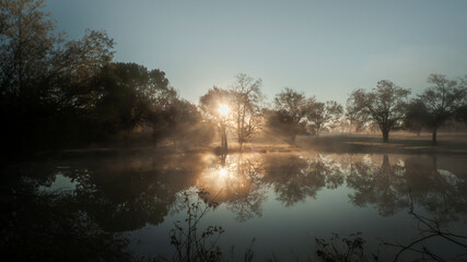 Fototapeta na wymiar Sunbeams and reflections on a foggy dawn