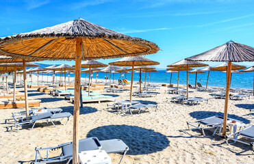 Reed umbrellas and sun beds at the empty beach in Asprovalta