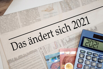 Newspaper with money and calculator and german headline Changes coming in 2021 - das ändert sich...