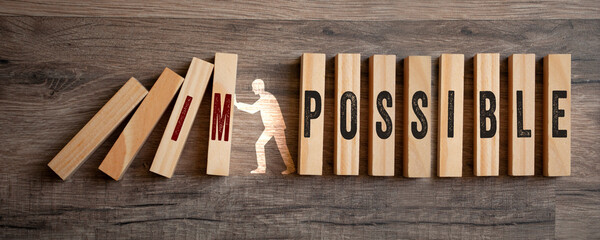 Pieces of wood with impossible and possible on wooden background