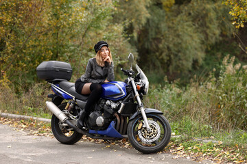 Fototapeta na wymiar Beautiful slim woman sitting on the motorcycle
