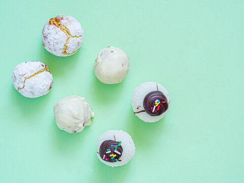 Assortment of white comfit and sweets in green background for dessert or tea time. Sweet chocolate treats. Flat lay food