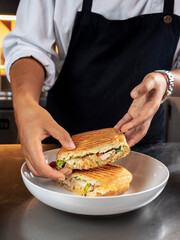 Closeup image of a female chef cooking and holding a piece of whole wheat sandwich in kitchen