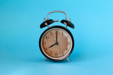 Wake up concept: alarm clock and cup of coffee mixed in one on blue background