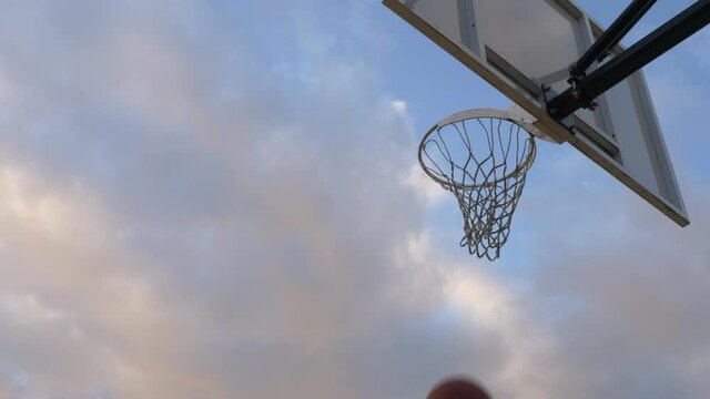 Basketball Player Doing A Reverse Layup Shot On The hoop In A Basketball Court. - low angle shot
