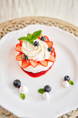 Pavlova is a meringue-based dessert with a crisp crust topped. Decorated strawberry, mint leaf, blueberry and whipped cream. Restaurant sweet food