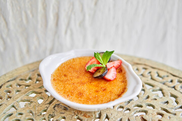 Classic creme brulee in glass bowl. Appetizing ice cream close up. Delicious dessert with grape and strawberry Sugary meal with caramel, mint and berries decoration. Restaurant sweet food