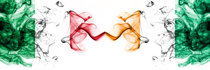 Italy vs Ivory Coast smoky mystic flags placed side by side. Thick colored silky abstract smoke flags