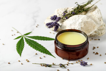 Obraz na płótnie Canvas Composition with cannabis wax salve or hemp face body cream with lavender extract and flowers