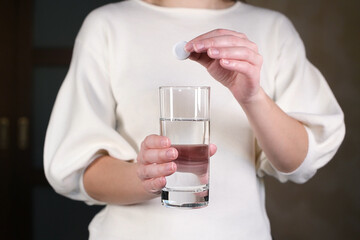 girl throws soluble effervescent tablets into a glass with water, without face