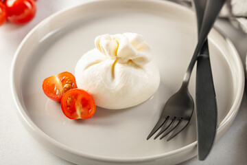 Italian cheese burrata with tomatoes on a plate with a fork