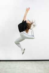 Young beautiful athletic girl dancing hip-hop in the studio