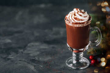 Hot chocolate cocoa with whipped cream in glass on dark background, copy space.