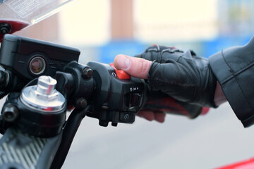 The biker puts his hand on the gas handle on the motorcycle, turns on the ignition and starts the...